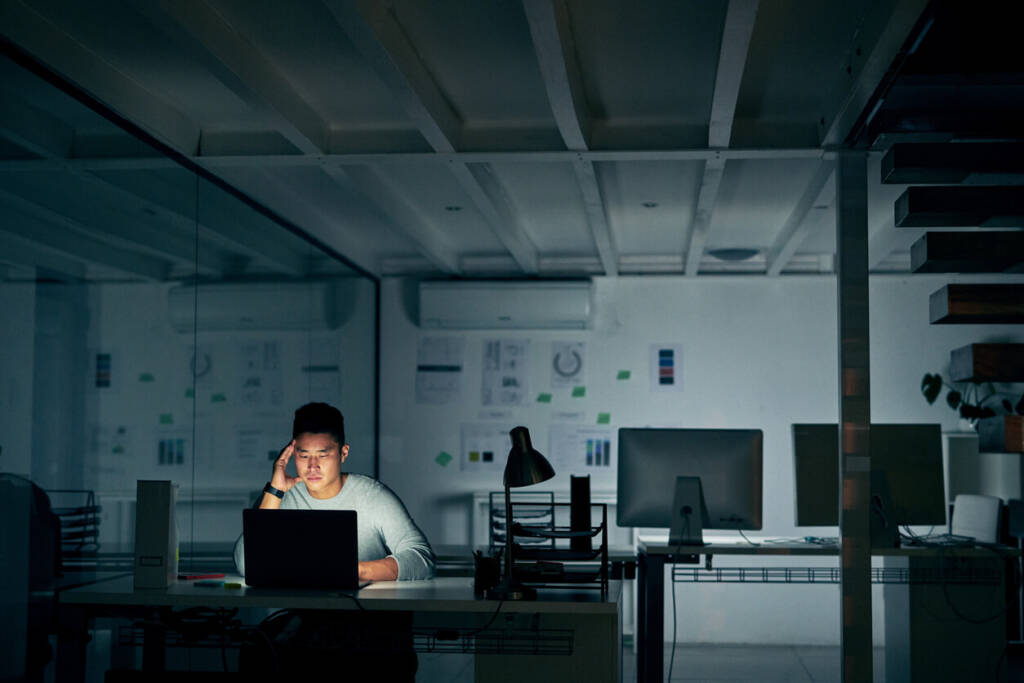 focused man sitting in a darkened office working at his laptop.