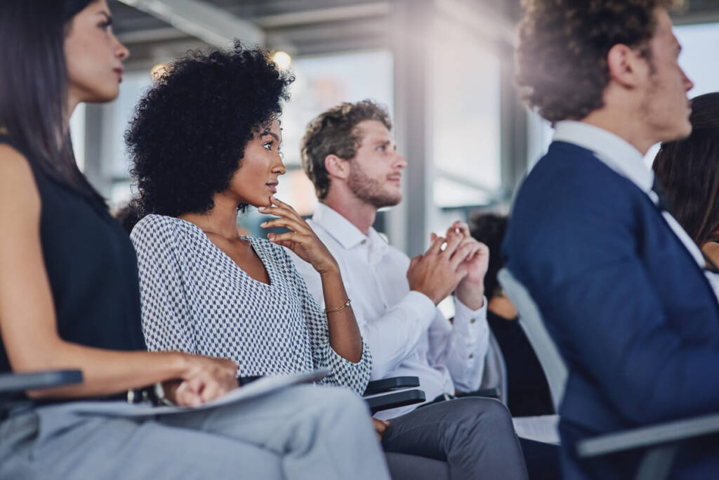 group of men and women sitting and listening